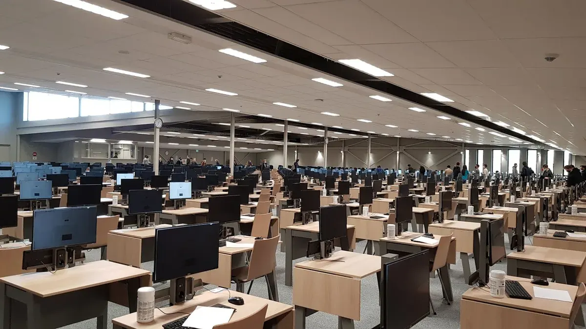 Sıralar halinde masaların bulunduğu geniş bir sınav salonu