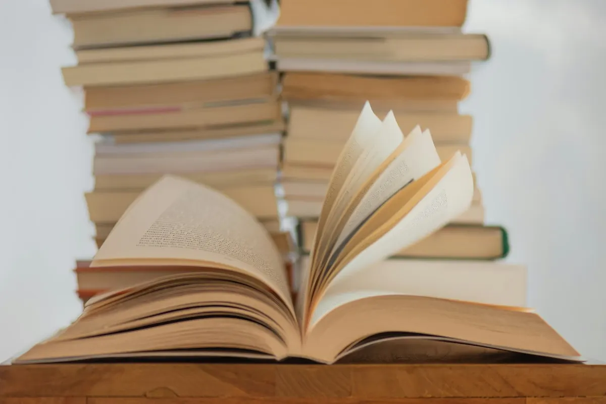 Üst üste dizilmiş kitapların önünde açık duran bir kitap